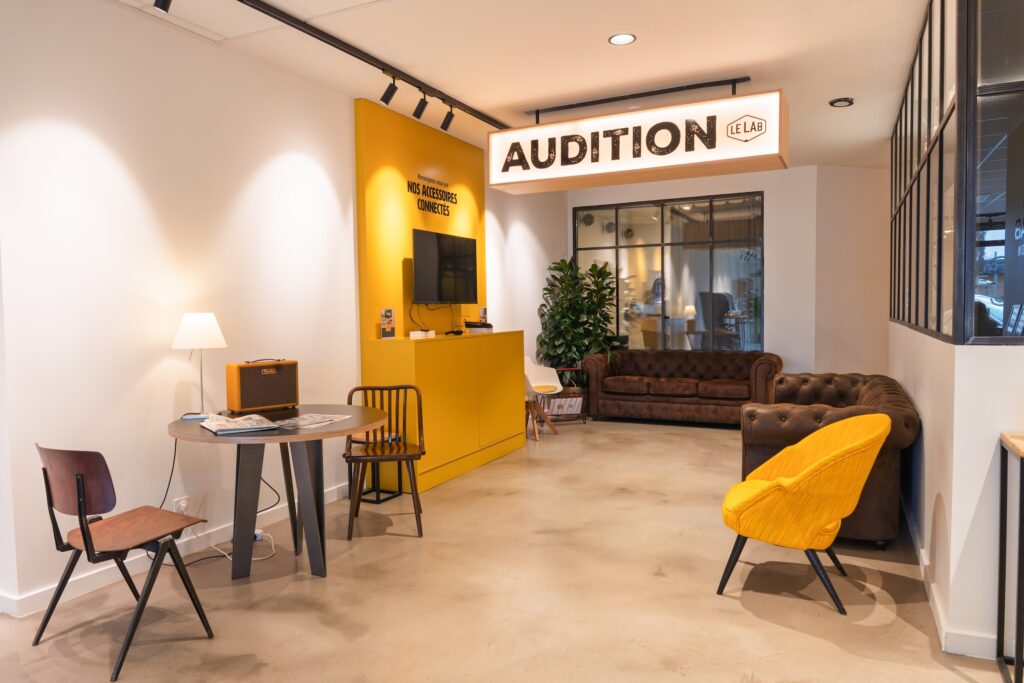 Espace intérieur du Lab Audition, représentant un espace avec fauteils, canapés et chaises et la partie "accessoires connectés".
